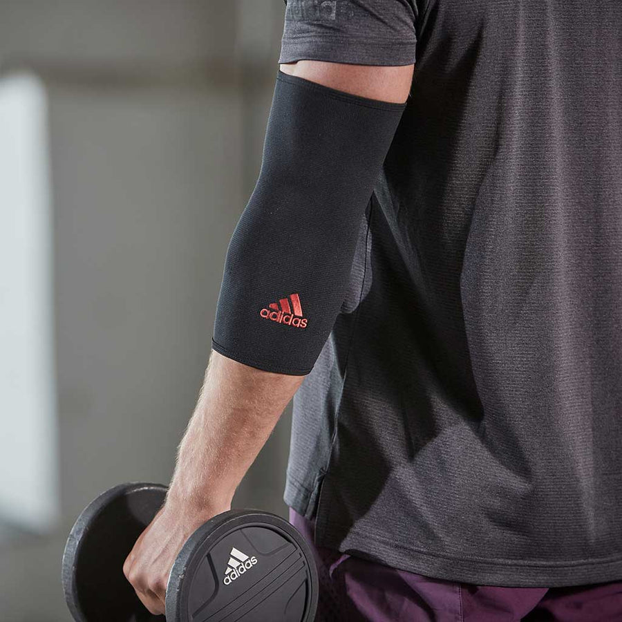 Man wearing adidas Essential Elbow Support while holding a dumbbell