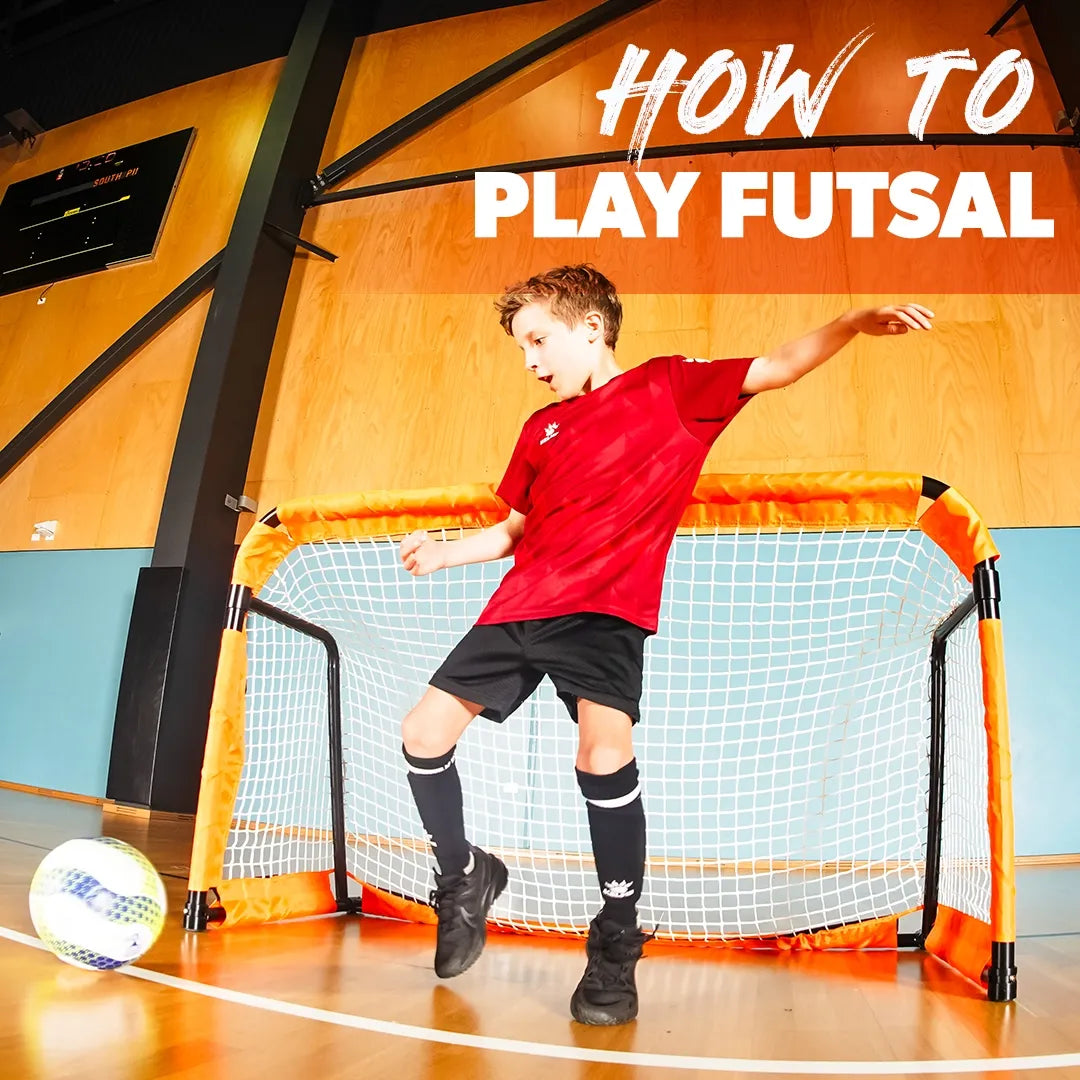 Boy playing futsal kicking futsal ball in front of portable soccer goal. 