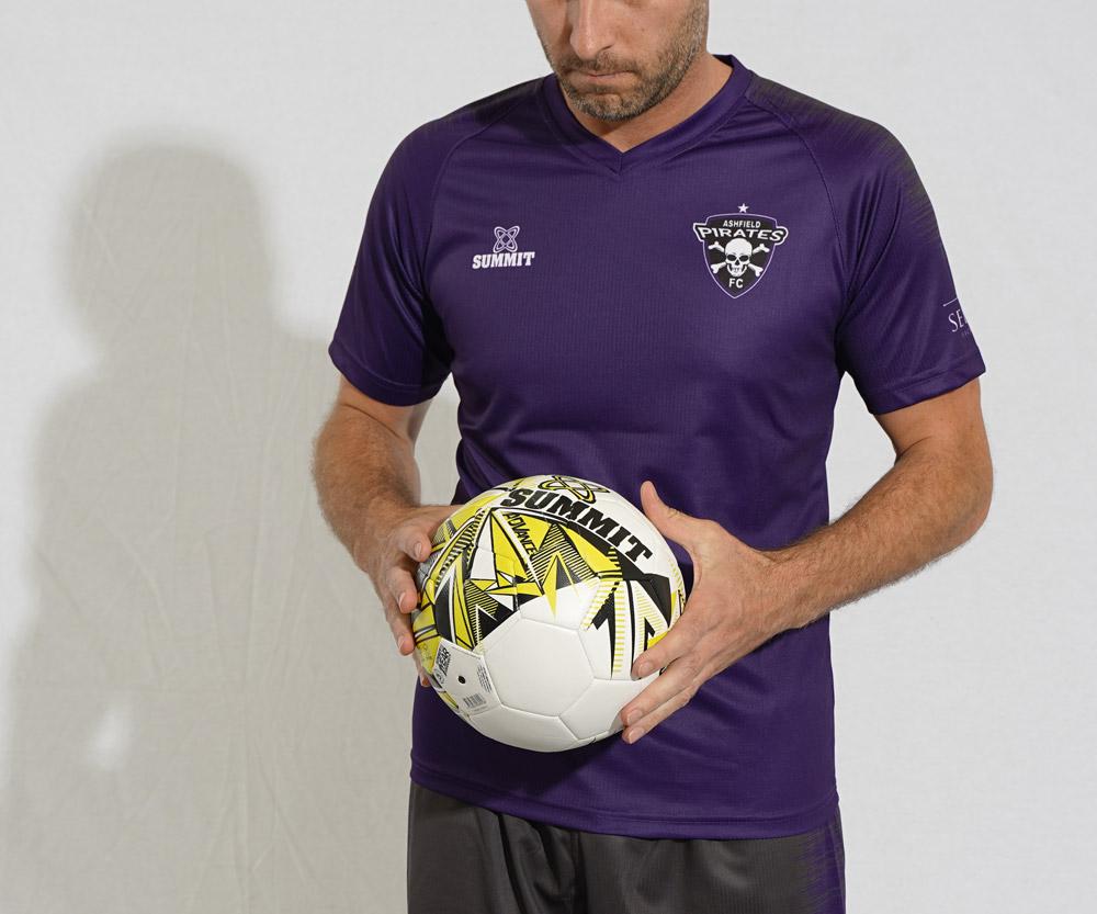 Footballer holding a soccer ball. The player is in a purple football jersey and getting ready to play a game of soccer. The soccer ball is a size 5 match ball.