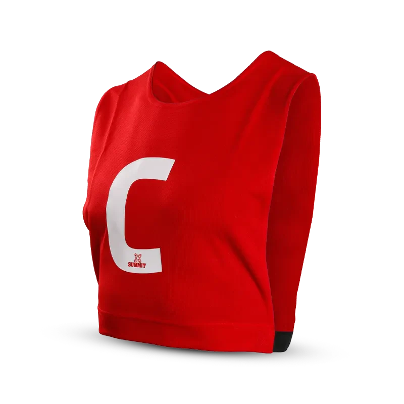Female netball player in Red Netball Bib with white WA - Wing Attack - position printed on front. Netball player is holding SUMMIT netball in size 5