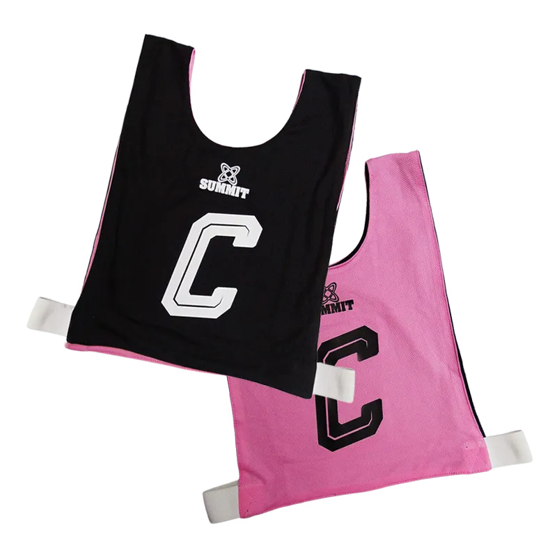Netball Girl in Reversible Netball bib in pink and black holding SUMMIT netball ball in size 5.