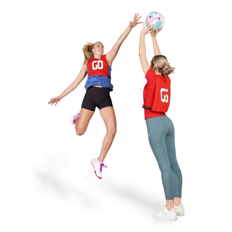 Netball players with Red Netball Bibs. Goal Shooter with GS printed and Goal Defence GD on bibs. GS is shooting and GD is defending