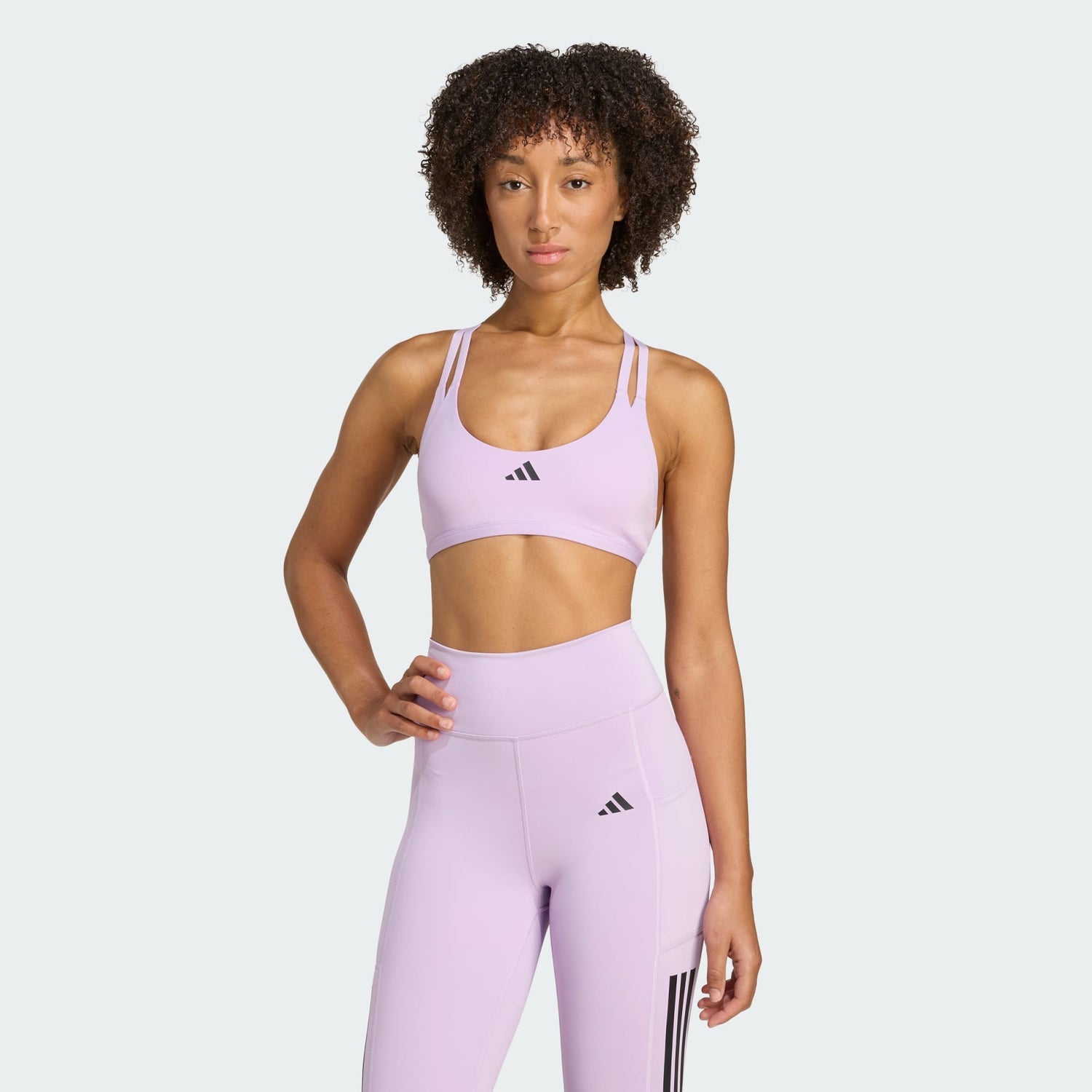 Woman wearing a lavender Adidas sports bra and leggings on a white background