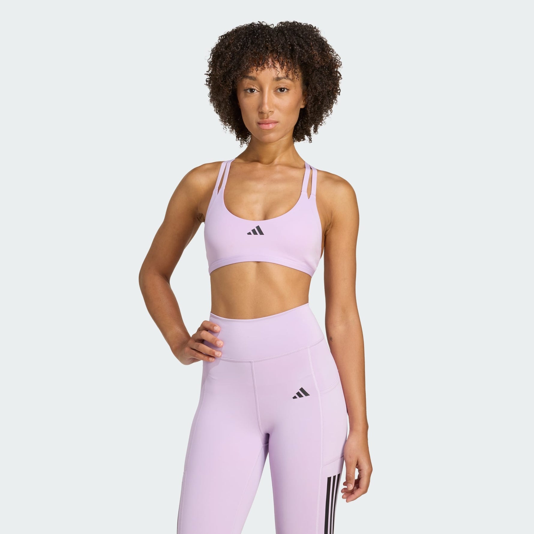 Woman wearing a lavender Adidas sports bra and leggings on a white background