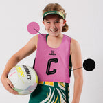 Junior reversable netball bib. Black and Pink netball bib for kids to play or train netball. Young tween girl netballer is wearing a pink netball bib.