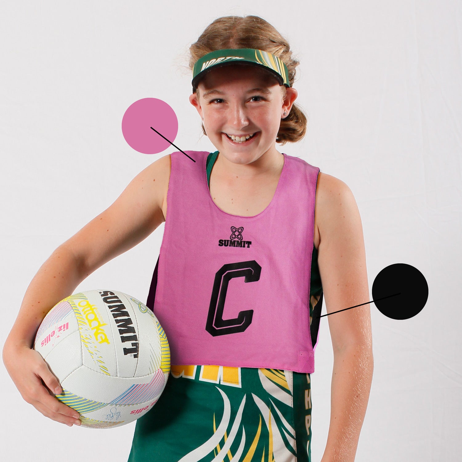 Junior reversable netball bib. Black and Pink netball bib for kids to play or train netball. Young tween girl netballer is wearing a pink netball bib.