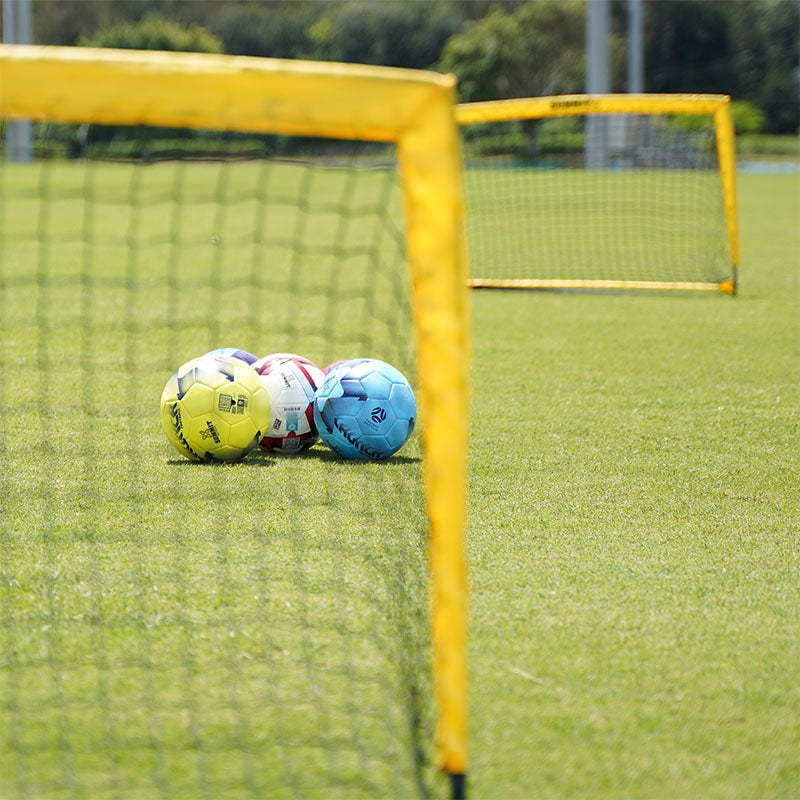 Set of two 4FT SUMMIT x Football Australia rectangular goals, out of focus, with soccer balls in focus between them