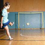 Person kicking a futsal ball towards football australia 3x2m flex futsal soccer goal on an indoor sports court.