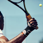 Person wearing adidas Wrist Support while holding a tennis racquet, about to hit tennis ball