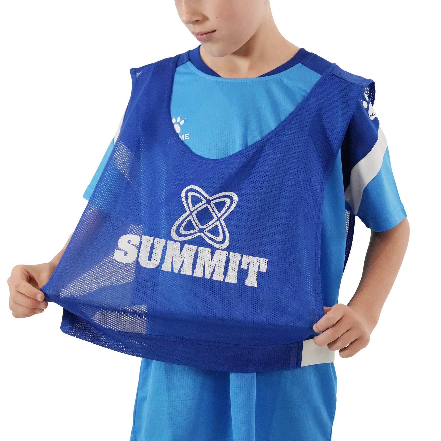 A child wearing a blue Summit athletic training bib over a light blue soccer jersey, holding the bottom of the bib open against a white background.