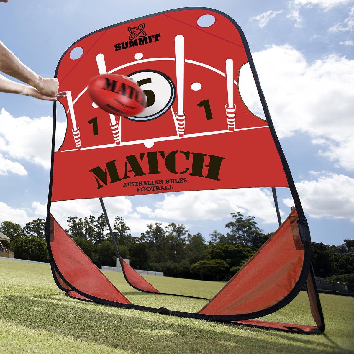 AFL player handballing red leather AFL ball into pop up target on grass ground. AFL pop up target made by SUMMIT Sport