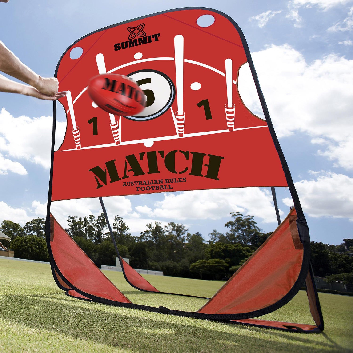 AFL player handballing red leather AFL ball into pop up target on grass ground. AFL pop up target made by SUMMIT Sport