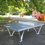 CORNILLEAU Pro Park Outdoor Table Cornilleau in open outdoor park with 2 table tennis bats and ball. Outdoor public table tennis table is fixed into place so it can be used for free by anyone.