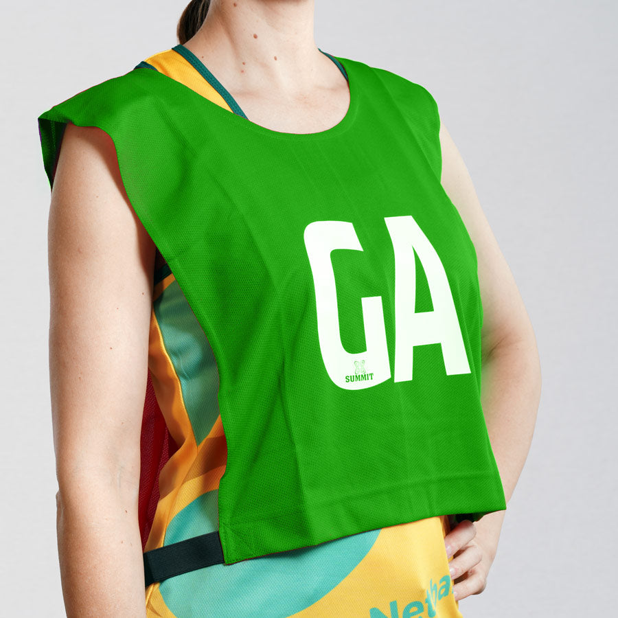 Goal Attack GA netball bib on young netball player. Green netball bib with elastic sides for easy fitment. Comes in a pack of 7 for netball teams