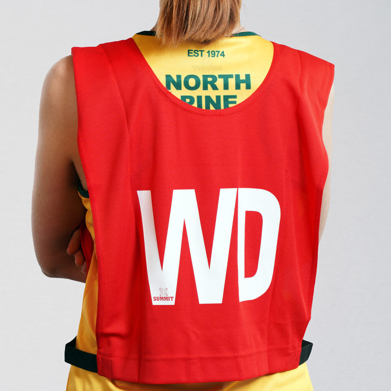 Wing Defence netball bib on young netball player. Red netball bib with elastic sides for easy fitment. Comes in a pack of 7 for netball teams