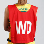 Wing Defence netball bib on young netball player. Red netball bib with elastic sides for easy fitment. Comes in a pack of 7 for netball teams