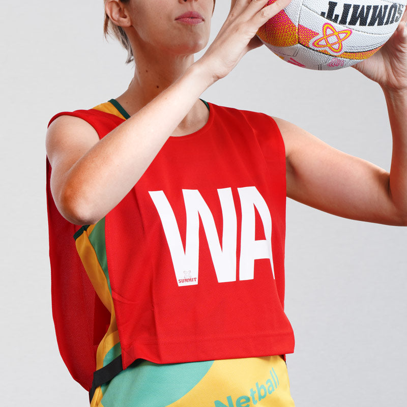 Netball bib being used by female netball player with SUMMIT Netball. Red Netball Bib for Wing Attack (WA) position. Shop netball bibs.