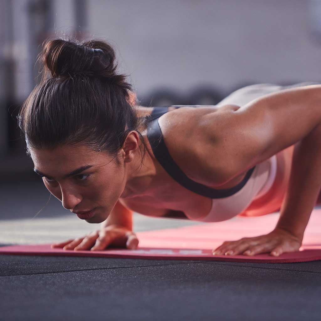 Female uses adidas 7mm fitness mat in red to complete her workout.